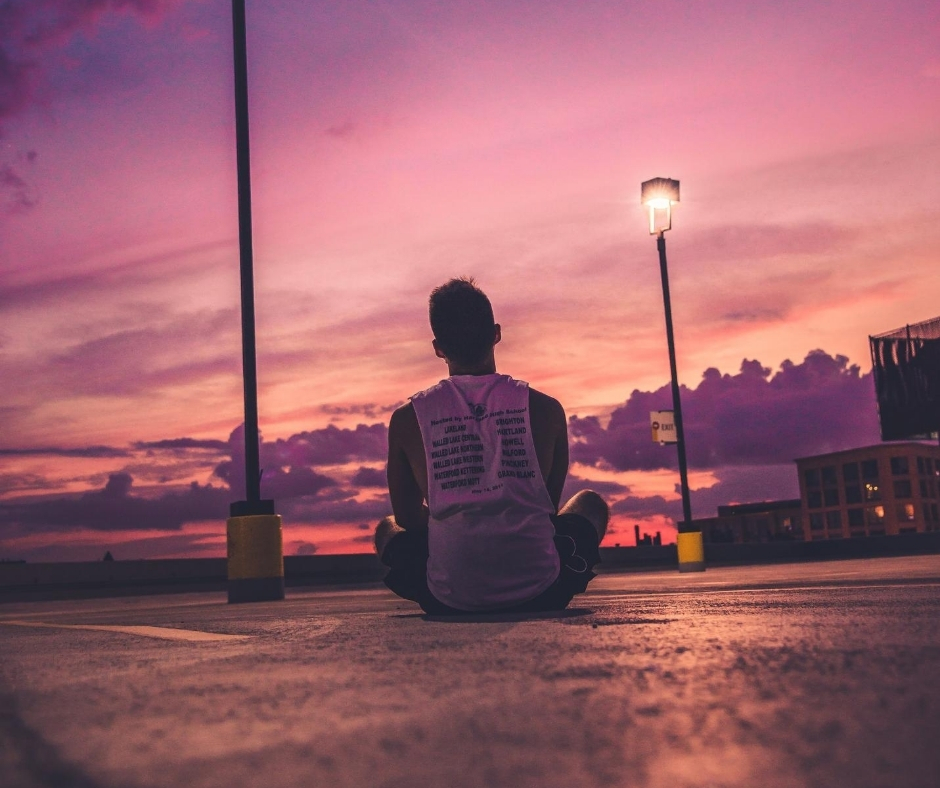 Man Sitting On Ground At Sunset