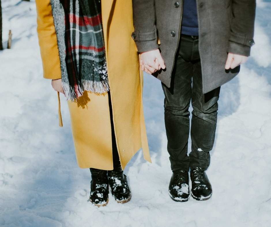 Lower Half Of Two People Standing In Snow