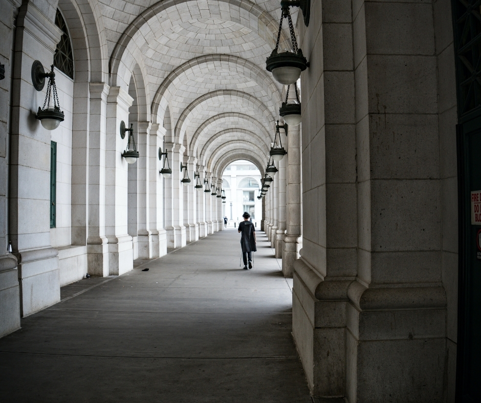 Person Walking Under Arches Of Higher Education